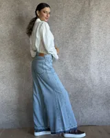 Pantalón de jean azul de tiro medio, con corte wide leg y ruedo deshilachado.