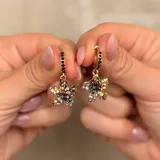Aros tipo argolla con dije colgante en forma de estrella, decorados con cristales en tonos negros, dorados y plateados.