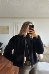 Campera reversible de corte recto y largo a la cadera. Un lado presenta un acabado de napa negra, mientras que el otro lado está confeccionado en piel sintética de color azul noche, extremadamente suave al tacto. Cuenta con mangas largas y un diseño versátil y elegante.