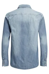 Camisa de denim celeste de manga larga, con cuello clásico, cierre frontal con botones a presión y dos bolsillos con solapa abotonada en el pecho.