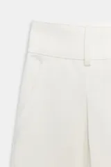 Bermuda larga cargo color blanco, con pinzas delanteras, bolsillos laterales de plastrón con solapa, cierre frontal con cremallera y botón.