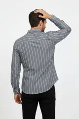 Camisa gris de manga larga con diseño de rayas verticales blancas, cuello camisero, cierre frontal de botones y corte recto.