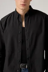 Camisa de manga larga color negro lavado, con cuello camisero con botones y cierre frontal abotonado.
