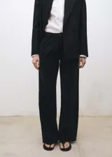 Pantalón de jean estilo wideleg color negro, con tiro medio, cierre frontal de cremallera y botón, trabillas para cinturón, bolsillos laterales y detalle de pinzas delanteras.
