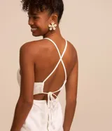 Mono largo blanco de sarga con escote en pico, tirantes finos, lazo en la espalda y cierre con cremallera.