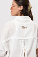 Camisa de lino blanca con silueta amplia y larga, con abertura vertical en la espalda y tiras para atar.