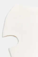 Top liso de punto color blanco crudo, con cuello barco y mangas cortas que presentan aberturas tipo cut-out.
