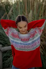 Sweater rojo de lana merino con cuello redondo y mangas largas. Presenta un canesú con diseño geométrico multicolor en tonos blanco, rojo, azul, verde y rosa.