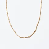 Cadena dorada con eslabones retorcidos y pequeñas cuentas esféricas.