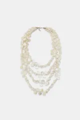 Collar de múltiples capas compuesto por pequeñas piezas circulares con acabado efecto nácar. Presenta un diseño voluminoso y cierre de mosquetón metálico.