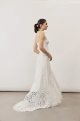 Vestido largo de encaje blanco con tirantes finos y silueta ajustada.