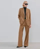 Blazer de corte sastrero en color tostado, con solapas clásicas, cierre frontal de dos botones y bolsillos laterales con solapa.