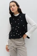 Chaleco de punto color celeste, con diseño de trenzas y pequeñas flores bordadas a mano en color marrón oscuro. Presenta cuello redondo y terminaciones acanaladas.