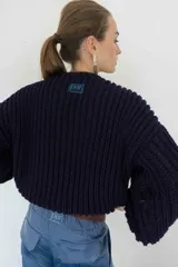 Sweater tejido de punto grueso color azul marino, con mangas anchas y logo bordado en azul en la parte superior de la espalda.