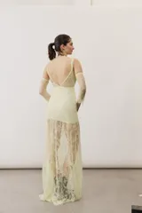 Vestido largo blanco de encaje con diseño asimétrico, tirante fino en un hombro y falda transparente.