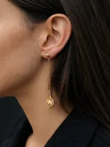 Aros largos con diseño de cadena y dije esférico calado que envuelve una perla de agua dulce central. Cuentan con aguja de plata 925 y acabado en chapado de oro 18k.