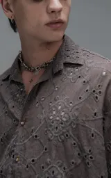 Camisa de manga corta con calce oversize y cuello abierto, confeccionada en algodón con diseño de bordado tipo broderie y efecto de desgaste en el color.