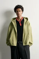 Cazadora relaxed fit de hombre, confeccionada en tejido estructurado tipo waffle con efecto lavado en color verde. Cuenta con cuello con capucha, cierre frontal con cremallera, bolsillos frontales tipo canguro y acabados elásticos en puños y bajo.
