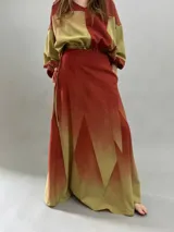 Falda larga de lana con diseño de paneles geométricos y efecto degradado que transiciona de verde esmeralda a tonos amarillentos. Presenta cintura alta, cierre invisible lateral y bolsillos ocultos.