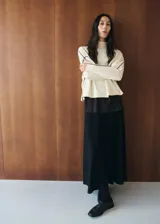 Chaleco de punto color blanco con detalles de líneas negras en los hombros y sisas, cuello alto y diseño holgado.