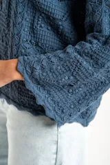 Sweater de tejido de punto calado color marrón, con diseño oversize, cuello redondo y mangas tres cuartos.