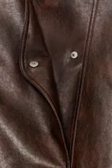Chaqueta bomber de efecto piel en color marrón oscuro, con cuello subido, cierre frontal cruzado con botones a presión, bolsillos laterales y bajo elástico.