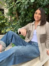 Camisa color beige con botones, de mangas largas y dos bolsillos frontales con solapa de cuero sintético color plateado.