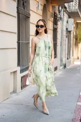 Vestido largo de corte holgado con escote halter y lazo ajustable en el cuello. Presenta un estampado tipo tie-dye en tonos verdes y crema, con un cinturón fino del mismo tejido para ajustar la cintura y bolsillos laterales.