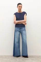 Jean wide leg bicolor en tonos de gris oscuro, con paneles laterales más oscuros y ruedo deshilachado.