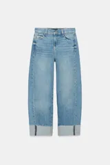 Jeans baggy de tiro medio con pernera holgada, diseño de cinco bolsillos y bajo acabado en vuelta. Cuenta con cintura elástica en la espalda y cierre frontal con cremallera y botón.