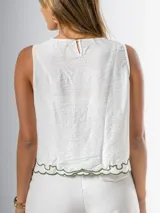 Musculosa blanca con bordado floral verde, cuello redondo y corte holgado.
