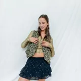 Chaleco corto con estampado abstracto en tonos dorados y azules, escote en V y cierre frontal con botones de madera.