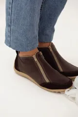 Zapatito marrón de cuero con puntera de gamuza, cierre frontal con cremallera y tirador trasero.