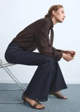Jeans tiro alto estilo flare de tejido vaquero de algodón con elasticidad, diseño largo con cinco bolsillos, trabillas y cierre frontal con botón y cremallera.