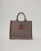 Bolso tote marrón con rayas verticales verde agua. Tiene doble asa corta marrón con rayas verde agua y etiqueta cuadrada con el nombre de la marca en el frente.