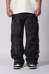 Jean baggy de corte holgado en color negro lavado. Presenta múltiples bolsillos cargo con cierre metálico en la parte frontal de las piernas, detalle de recortes en la espalda y tiras de ajuste en los tobillos.