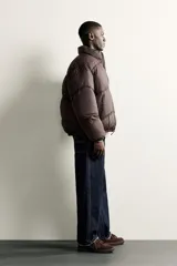 Cazadora acolchada tipo puffer de corte relajado, color negro, con cuello subido, cierre frontal de cremallera y bolsillos laterales con cierre. Presenta puños y ruedo con terminación elástica.