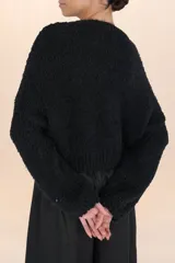 Suéter negro de tejido suave y esponjoso, con cuello redondo y mangas amplias de volumen.