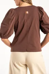 Remera de algodón negro con mangas cortas abullonadas, cuello redondo y costura central frontal.