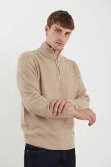 Sweater verde de punto inglés con cuello alto y cierre metálico frontal. Tiene mangas largas y terminaciones en punto canalé.