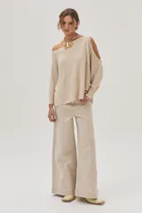 Top tejido color beige, de mangas largas y corte asimétrico con hombros descubiertos.