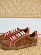 Championes marrones de cuero con cordones intercambiables blancos y rosas, y logo bordado en el lateral.