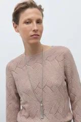 Sweater de punto color beige claro, con escote bote y tejido calado con diseño ondulado. Es de manga larga y corte recto.