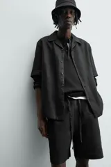 Bermuda de lino color blanco hueso, de corte relajado y tiro medio. Presenta cintura elástica ajustable con cordón, pliegues frontales y bolsillos laterales y trasero.