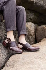 Zapato destalonado de cuero marrón con puntera cerrada, detalles de textura grabada en la capellada y tira ajustable con hebilla en el talón, con taco bajo y ancho.