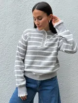 Sweater de punto a rayas horizontales blancas y negras, con cuello redondo, cierre frontal con botones y detalles de puntilla en el cuello y los puños.