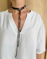 Gargantilla negra de cuero con dije metálico dorado en forma de anillo.