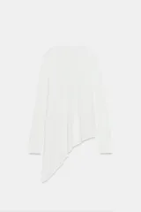 Jersey de punto liso blanco, con cuello redondo y mangas largas. Presenta un diseño de bajo asimétrico pronunciado.
