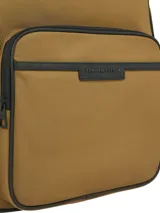 Mochila Tommy Hilfiger color marrón con ribetes negros. Cuenta con un compartimento principal con cierre de doble cremallera, un bolsillo exterior con cremallera, asa superior, correas ajustables y acolchadas, panel de malla acolchado en la parte trasera, funda para portátil incorporada y logo metálico de Tommy Hilfiger en la parte delantera.