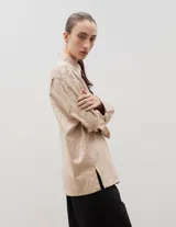 Camisa de corte holgado y diseño clásico, confeccionada en tela satinada con un sutil estampado floral tono sobre tono. Presenta cuello camisero, cierre frontal con botones y mangas largas con puños rectos.